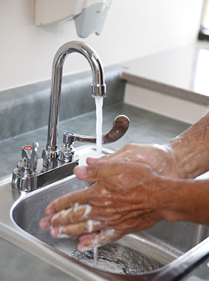 Gros plan de mains se lavant avec du savon et de l'eau.